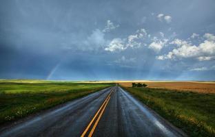 Regenbogen und nasse Landstraße in Saskatchewan foto