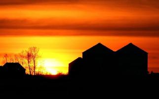 untergehende Sonne hinterleuchtet landwirtschaftliche Gebäude foto