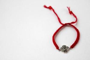 rotes geflochtenes Armband mit Chakra Muladhara auf der rechten Seite des weißen Hintergrunds foto