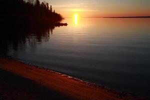 reflektierter Sonnenaufgang am Ufer des Lake Winnipeg