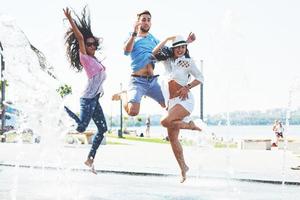 gruppe von freunden, die sich an sommertagen neben dem öffentlichen brunnen vergnügen foto