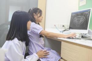 Zahnärztin erklärt einem kleinen Mädchen in der Zahnklinik die Röntgenaufnahme der Zähne, die Zahnuntersuchung und das Konzept der gesunden Zähne foto
