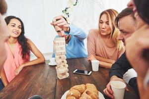 Gruppe kreativer Freunde, die am Holztisch sitzen. Leute, die Spaß beim Brettspiel haben foto