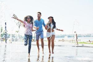 gruppe von freunden, die sich an sommertagen neben dem öffentlichen brunnen vergnügen foto