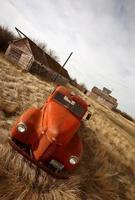 Alter landwirtschaftlicher Lastwagen, der in der Nähe von ungenutzten Holzgebäuden aufgegeben wurde foto