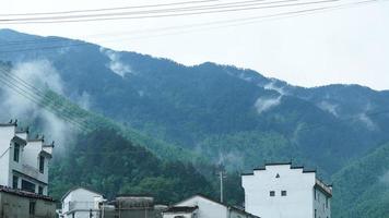 stadt wuyuan, provinz jiangxi, china, 2021 - die wunderschönen berglandschaften mit dem grünen wald und dem kleinen dorf als hintergrund in der landschaft des chinas foto