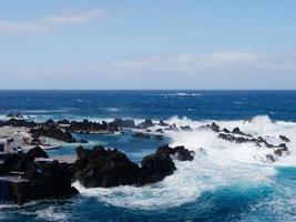 natürliche pools mitten im atlantik in porto moniz, madeira, portugal. tolle Urlaubszeiten. Wolken mit Sonne. Ozean und Wellen, die die Felsen treffen. Menschen im Wasser. foto