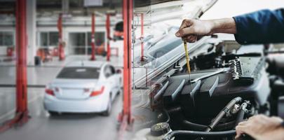 automechaniker überprüft den motorölstand in der autowerkstatt, wartung autoarbeiterinspektion überprüft ölfahrzeugmotoren durch ölmessstabtest an der autowerkstattstation. Auto Auto Dienstleistungen foto