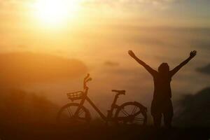 Silhouette des Menschen hob seine Hand mit einem Fahrrad vor Sonnenuntergang Hintergrund. foto