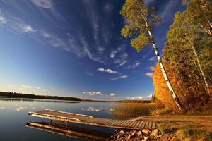 Bootsdock und Bäume im Herbst entlang eines Sees in Saskatchewan foto