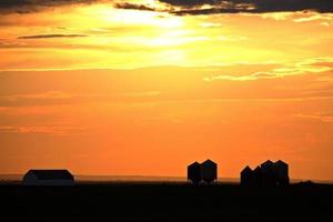 untergehende Sonne, die landwirtschaftliche Gebäude im malerischen Saskatchewan beleuchtet foto