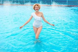 schönes lächelndes Rotkopffrauenporträt, das das Leben im Schwimmbad am Sommertag genießt. Sommer, Entspannung, Wellness, Reisen, Erholungskonzept foto