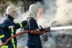 Feuerwehrmann sprüht Wasser aus einem großen Wasserschlauch, um einen Brand zu verhindern foto