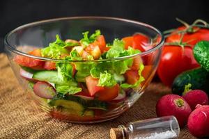 Salat aus frischem Gemüse in einer Glasschüssel auf dunklem Hintergrund. foto