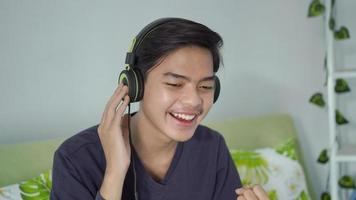 asiatischer mann, der glücklich von seinem headset zuhört foto