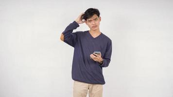 Schöner Mann verwirrt mit Smartphone in der Hand isoliert auf weißem Hintergrund foto