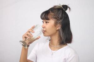 asiatische frau trinkt glas wasser auf weißem hintergrund isoliert foto