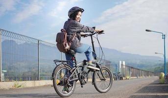 junge asiatische frau bricht fahrrad, bevor sie zur arbeit geht foto