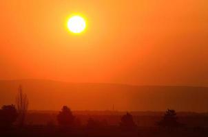 sonnenaufgang mit berg- und dorflandschaft foto