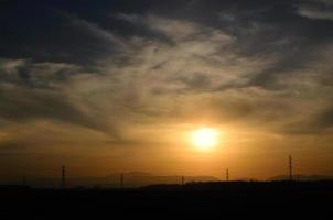 Sonnenuntergang mit Landschaft und Strommasten foto