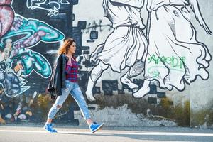 Teenager-Mädchen zu Fuß entlang einer Wand aus Graffiti