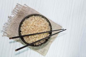 brauner Reis in Schüssel haben Stäbchen isoliert auf weißem Hintergrund foto