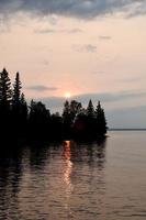 Ein Sonnenuntergang, der sich auf einem klaren See im Riding Mountain National Park in Manitoba, Kanada, widerspiegelt foto