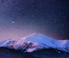 schöne Winterlandschaft in den Karpaten. lebendiger Nachthimmel mit Sternen und Nebel und Galaxien. Deep-Sky-Astrofoto foto