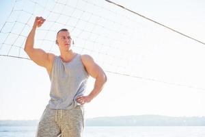 Ein sportlicher Mann, der am wilden Sandstrand auf das Meer blickt. maskuliner und sportlicher mann mit nacktem oberkörper macht abendtraining an der meeresküste. Sommer-Workout-Training im Freien foto