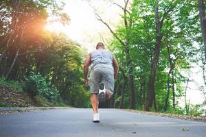 Outdoor-Cross-Country-Lauf im Konzept für Training, Fitness und gesunden Lebensstil. Nahaufnahme der Füße eines jungen Läufers, der im Park entlang der Straße läuft foto