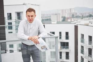 lächelnder junger Architekt oder Ingenieur mit Schutzhelm und Tablet über einer Gruppe von Bauherren auf der Baustelle, Architekt, der ein Konzept für Bau, Geschäft, Gebäude, Industrie und Menschen beobachtet foto