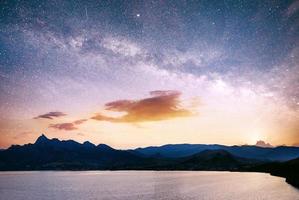 herrliches Panorama des Sonnenaufgangs über dem Meer. lebendiger Nachthimmel mit Sternen und Nebel und Galaxien. Deep-Sky-Astrofoto foto