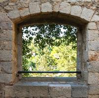 Fenster mit Blick auf den Garten in einer Backsteinmauer foto