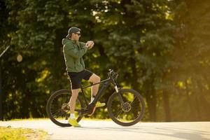 junger mann, der die zeit auf dem ebike in der natur überprüft foto