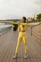 junge Frau mit Dehnübungen am Pier am Flussufer foto