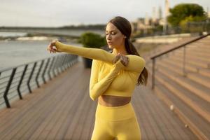 junge Frau mit Dehnübungen am Pier am Flussufer foto