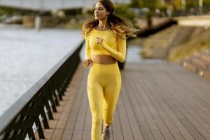 junge Frau, die auf dem Pier am Flussufer läuft foto