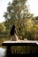 junge frau, die sich auf dem holzsteg am ruhigen see entspannt foto