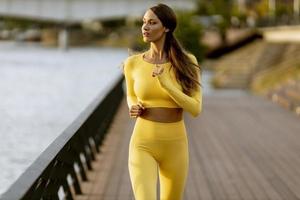 junge Frau, die auf dem Pier am Flussufer läuft foto