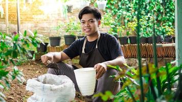 asiatischer mann bereitet einen platz zum pflanzen mit topf und erde vor foto