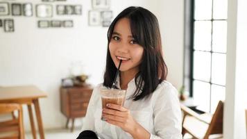 schöne junge asiatische geschäftsfrau im anzug, der eine braune kaffeetasse im caffe hält, während sie eine kaffeepause macht. foto