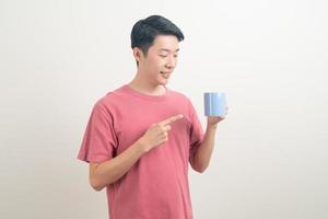 junger asiatischer mann, der kaffeetasse hält foto