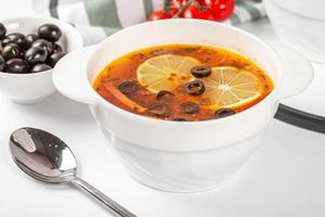 Suppe Soljanka mit Fleisch, Wurst, Gemüse, Gurken, Oliven und Zitrone