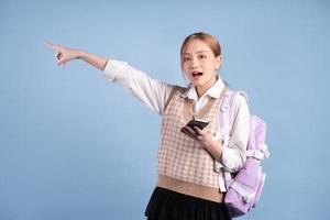 junges asiatisches Highschool-Mädchen auf blauem Hintergrund foto