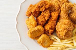 Brathähnchen mit Pommes Frites und Nuggets auf Teller foto