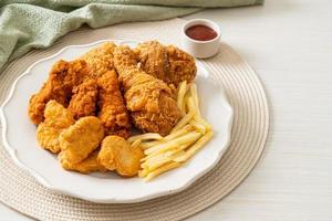 Brathähnchen mit Pommes Frites und Nuggets auf Teller foto