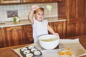 ein kleines braves mädchen backt leckere cupcakes foto