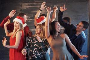 Party mit Freunden. sie lieben weihnachten. Gruppe fröhlicher junger Leute, die Wunderkerzen und Champagnerflöten tragen, die in der Neujahrsparty tanzen und glücklich aussehen. Konzepte zum Zusammengehörigkeitsleben foto