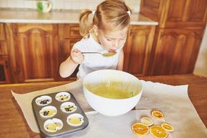 Ein kleines Mädchen bereitet einen Teig für Muffins zu. foto