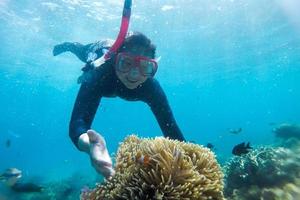 junge Frau, die an einem wunderschönen Riff mit Fischen am Strand von Karimun Jawa schnorchelt foto